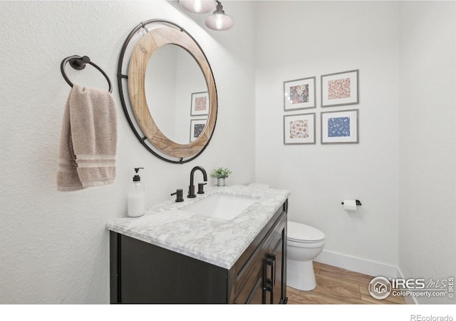 bathroom featuring vanity, wood-type flooring, and toilet