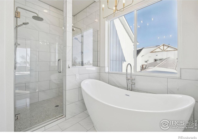 bathroom featuring tile walls, plus walk in shower, and a chandelier