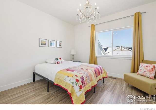 bedroom with hardwood / wood-style floors and a notable chandelier