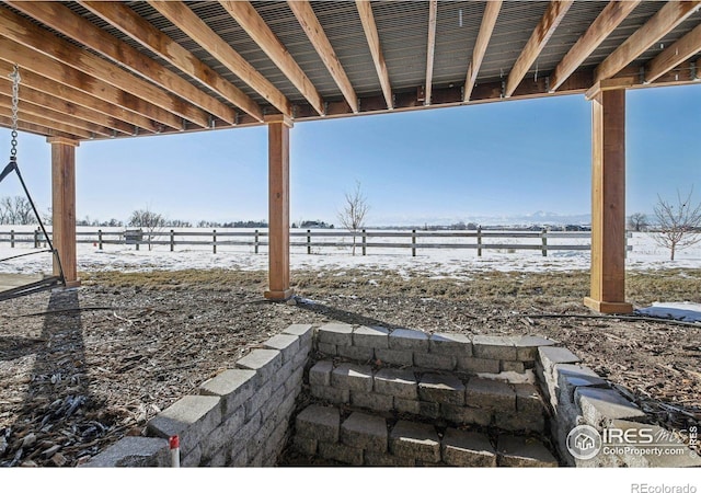 snow covered patio with a rural view