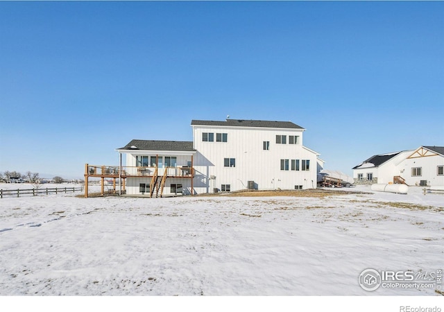 snow covered rear of property with a wooden deck