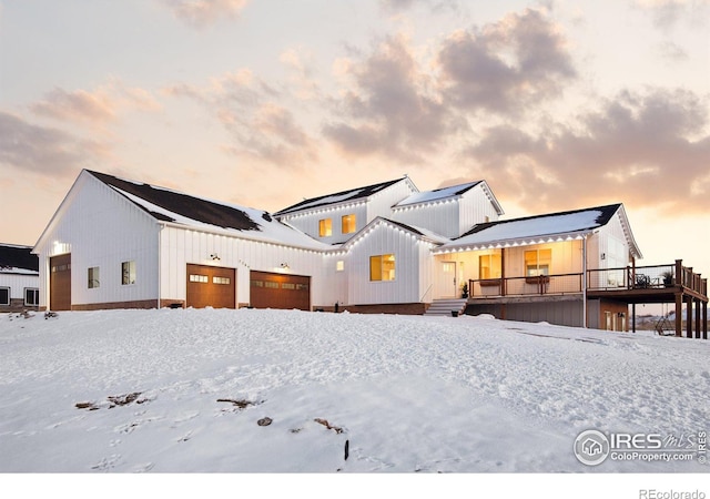 snow covered rear of property with a garage