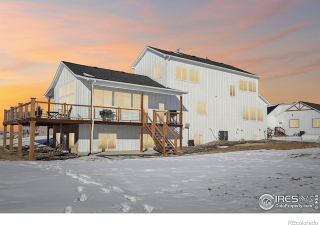 snow covered house featuring central AC and a wooden deck