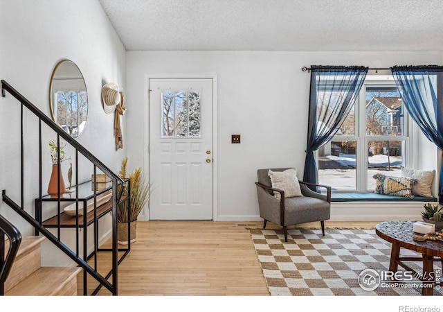 entryway with a textured ceiling, a healthy amount of sunlight, and light wood-type flooring