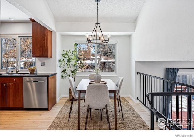 dining space with an inviting chandelier, sink, light hardwood / wood-style flooring, and a textured ceiling