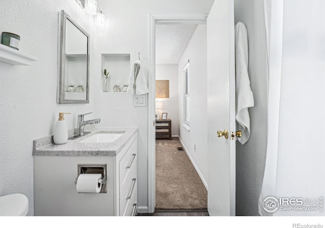 bathroom featuring vanity, toilet, and a textured ceiling