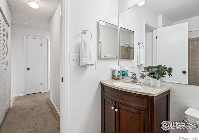 bathroom with vanity, toilet, and a textured ceiling