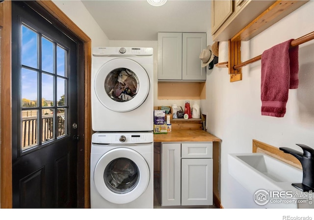 laundry room with cabinets and stacked washer and clothes dryer