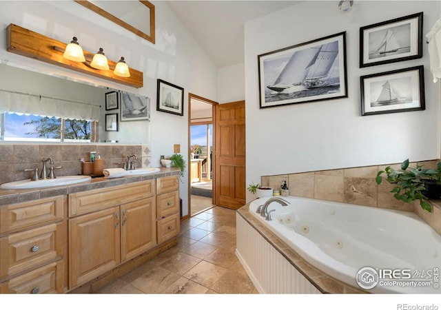 bathroom with lofted ceiling, vanity, decorative backsplash, tile patterned floors, and a bathing tub