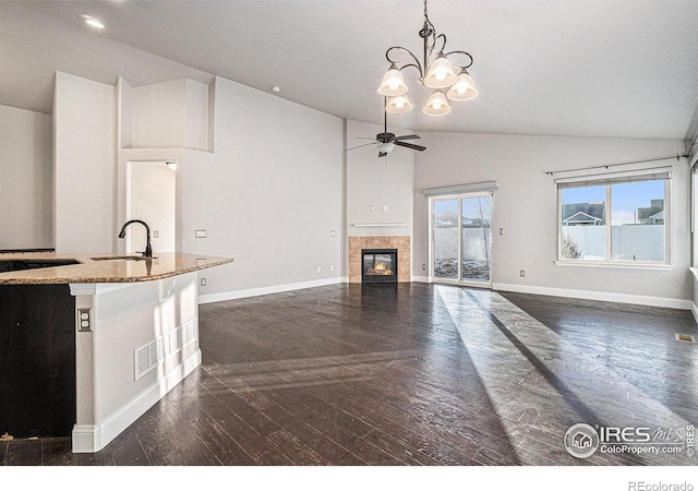 kitchen featuring pendant lighting, sink, dark hardwood / wood-style floors, light stone counters, and vaulted ceiling