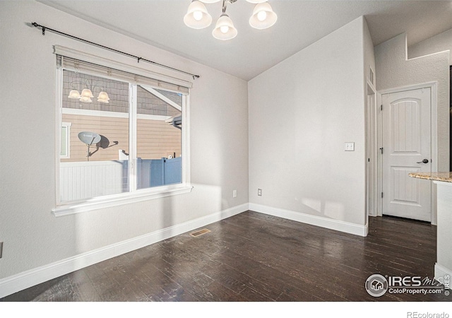 unfurnished room featuring lofted ceiling, an inviting chandelier, and dark hardwood / wood-style flooring