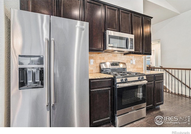 kitchen featuring dark brown cabinetry, stainless steel appliances, dark hardwood / wood-style flooring, and light stone countertops