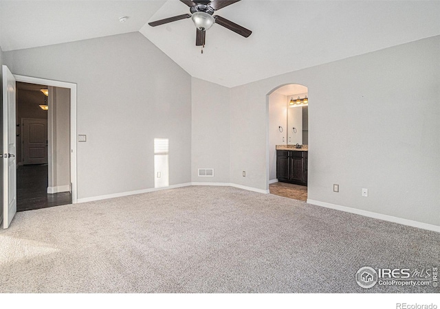 unfurnished bedroom featuring ceiling fan, lofted ceiling, light colored carpet, and ensuite bath