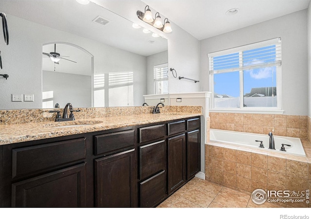 bathroom featuring a relaxing tiled tub, vanity, tile patterned floors, and ceiling fan