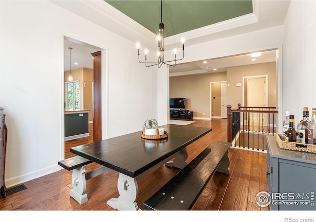 dining space featuring a raised ceiling, dark wood-type flooring, and an inviting chandelier