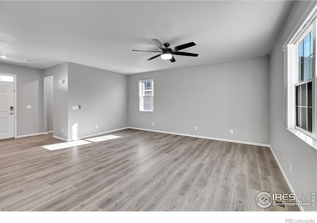 empty room with ceiling fan and light hardwood / wood-style flooring