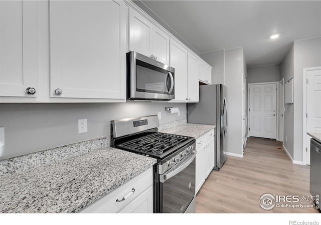 kitchen featuring white cabinetry, light stone countertops, light hardwood / wood-style flooring, and stainless steel appliances