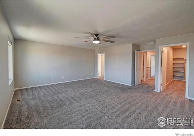 spare room with dark colored carpet, ceiling fan, and a textured ceiling