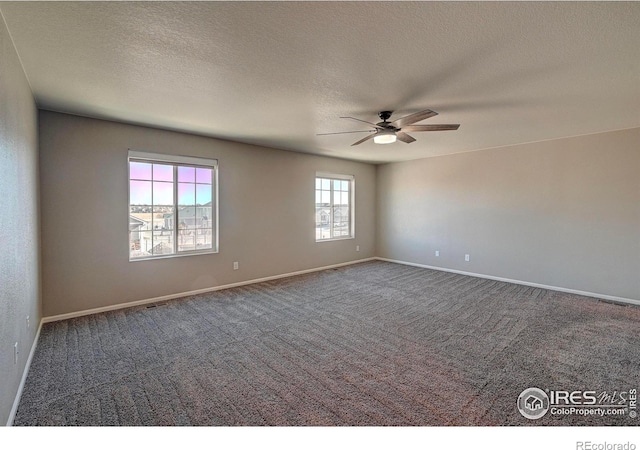 spare room featuring dark colored carpet, a textured ceiling, and ceiling fan