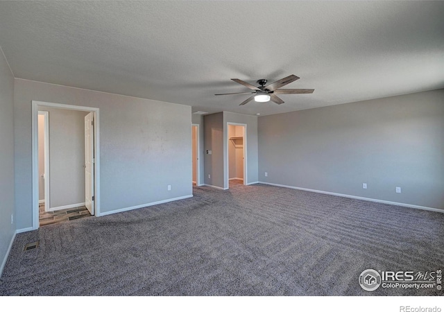 unfurnished room featuring ceiling fan, dark carpet, and a textured ceiling