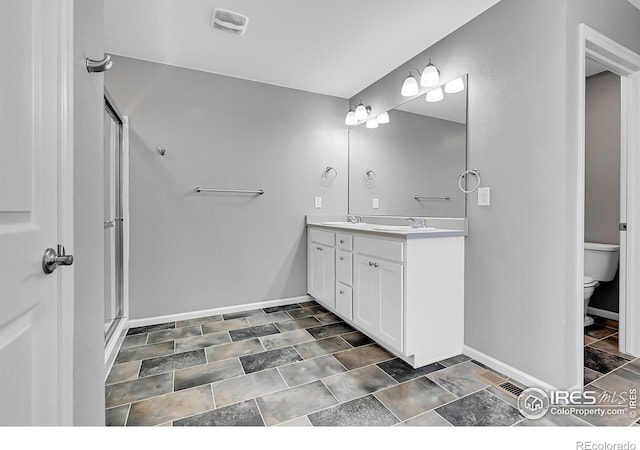 bathroom with a shower with door, vanity, and toilet