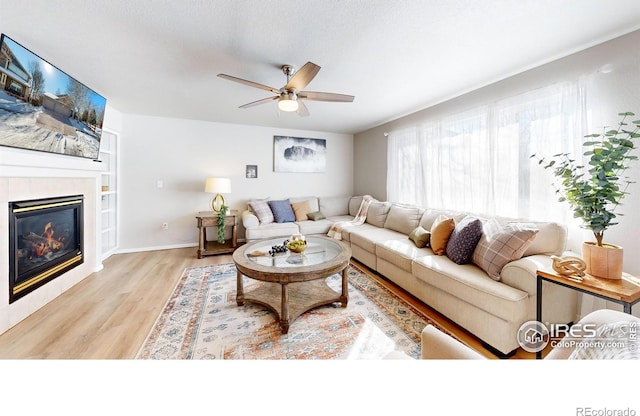 living room featuring ceiling fan, a textured ceiling, and light wood-type flooring