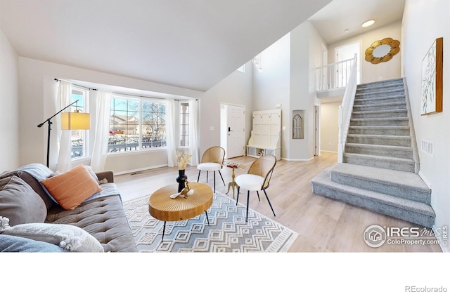 living room featuring a towering ceiling and light wood-type flooring