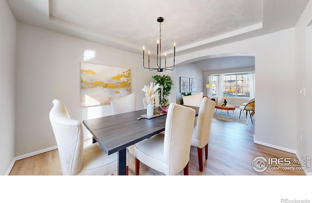 dining space featuring a notable chandelier, a tray ceiling, and hardwood / wood-style flooring