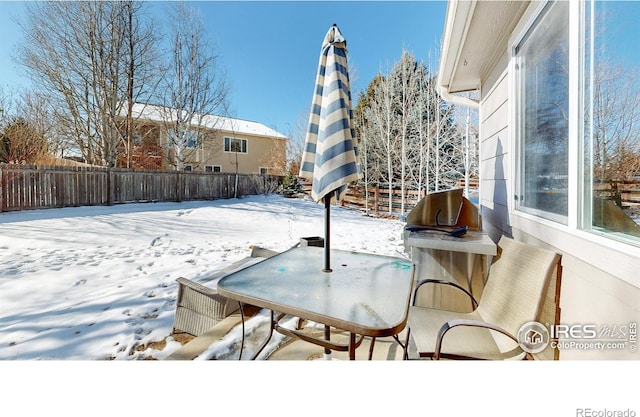 snow covered patio with a grill