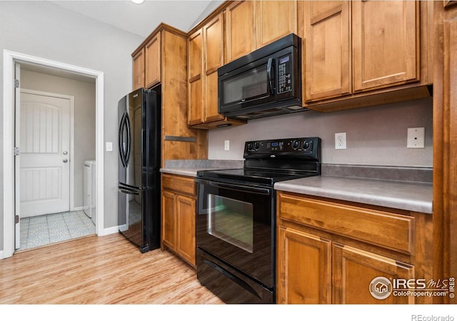 kitchen with separate washer and dryer, light hardwood / wood-style flooring, and black appliances