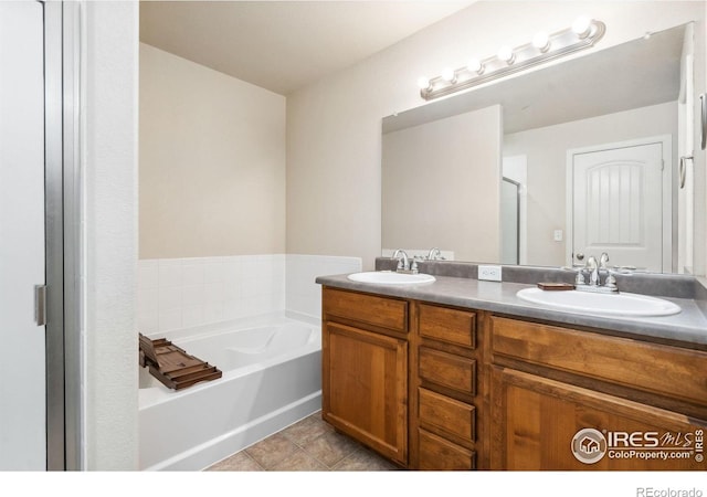 bathroom with a tub to relax in, tile patterned floors, and vanity