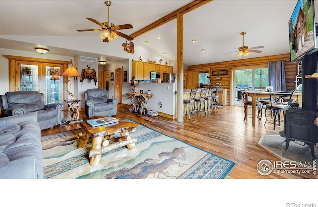 living room with ceiling fan, light hardwood / wood-style flooring, high vaulted ceiling, and rustic walls