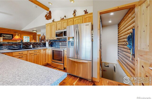 kitchen featuring light brown cabinetry, sink, stainless steel appliances, and vaulted ceiling with beams