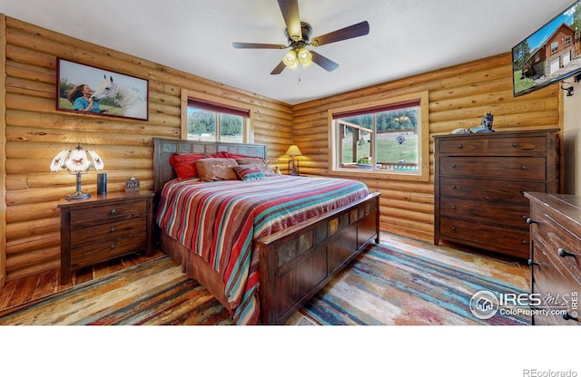 bedroom with rustic walls, ceiling fan, and light hardwood / wood-style flooring