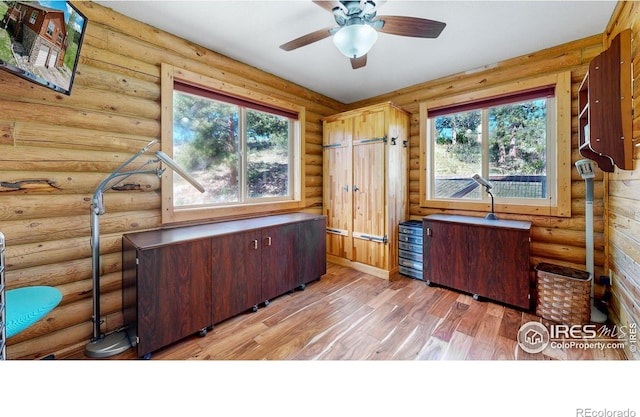 office featuring ceiling fan, light hardwood / wood-style floors, and rustic walls