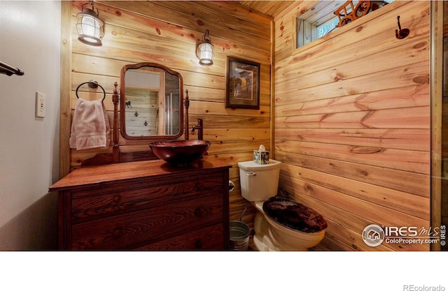 bathroom featuring vanity, toilet, and wood walls