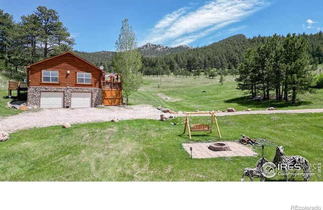 exterior space with an outdoor fire pit, a deck with mountain view, and a garage