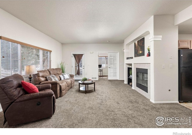 living room with a fireplace, built in features, a textured ceiling, and carpet