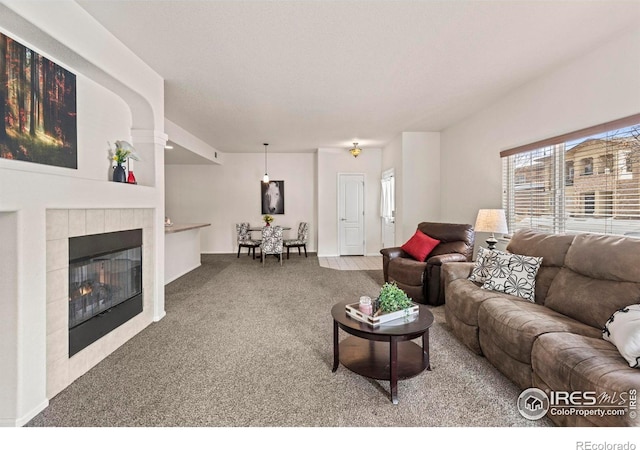 living room featuring a tiled fireplace and carpet