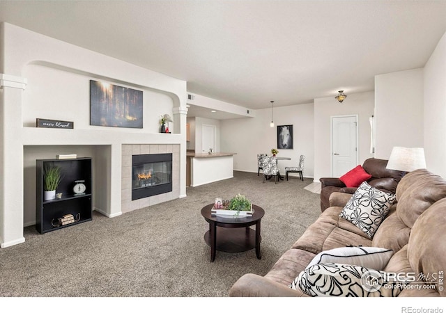 living room with a fireplace, ornate columns, and carpet