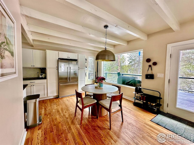 dining room featuring beamed ceiling and light wood-type flooring