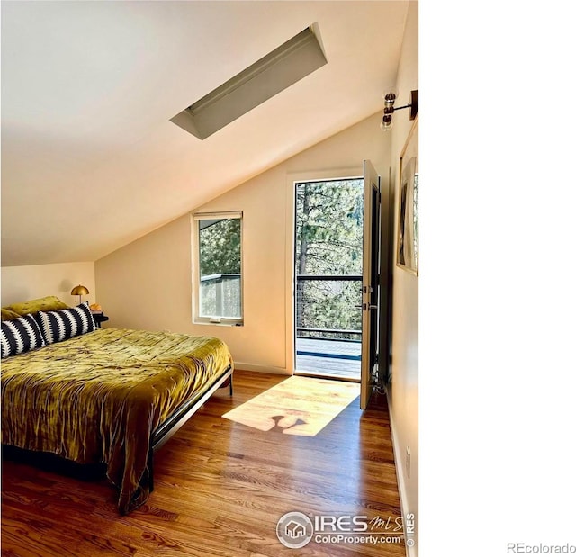 bedroom with lofted ceiling, hardwood / wood-style floors, and access to exterior