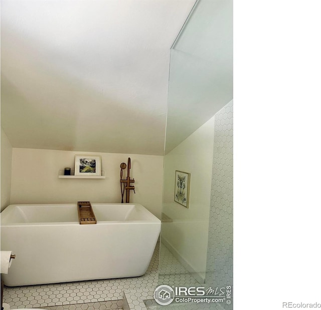 bathroom with lofted ceiling, tile patterned floors, and a tub