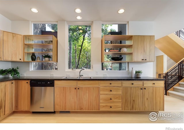 kitchen with light brown cabinetry, sink, dark stone counters, stainless steel dishwasher, and light hardwood / wood-style floors