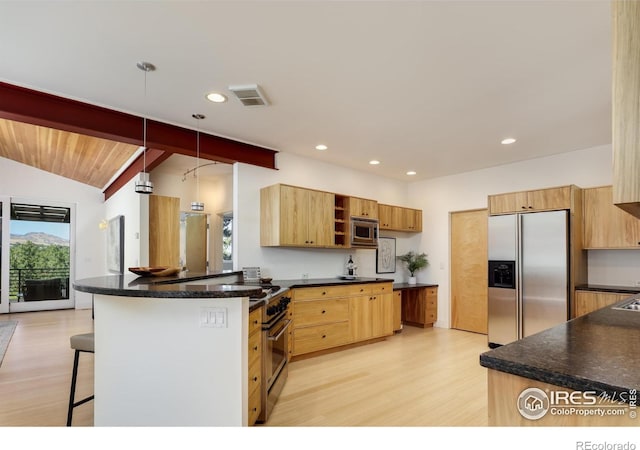 kitchen featuring lofted ceiling, a breakfast bar area, appliances with stainless steel finishes, decorative light fixtures, and kitchen peninsula