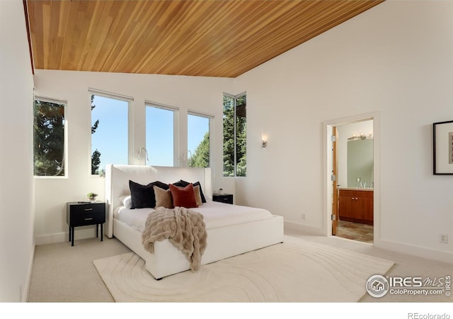 carpeted bedroom featuring vaulted ceiling, wooden ceiling, and ensuite bath