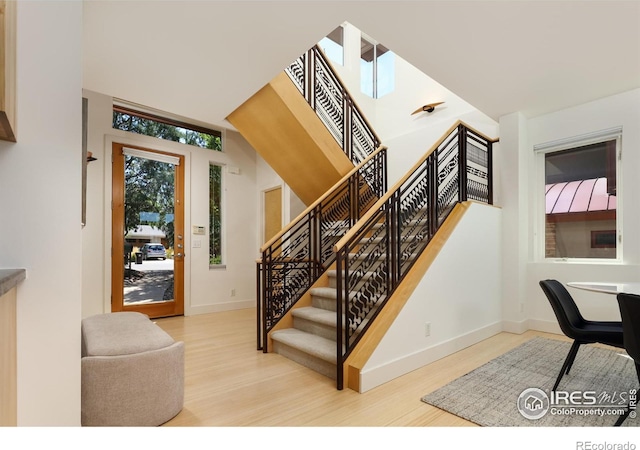 stairway with hardwood / wood-style flooring and a towering ceiling