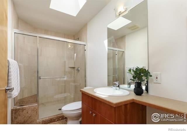 bathroom featuring toilet, walk in shower, vanity, and a skylight