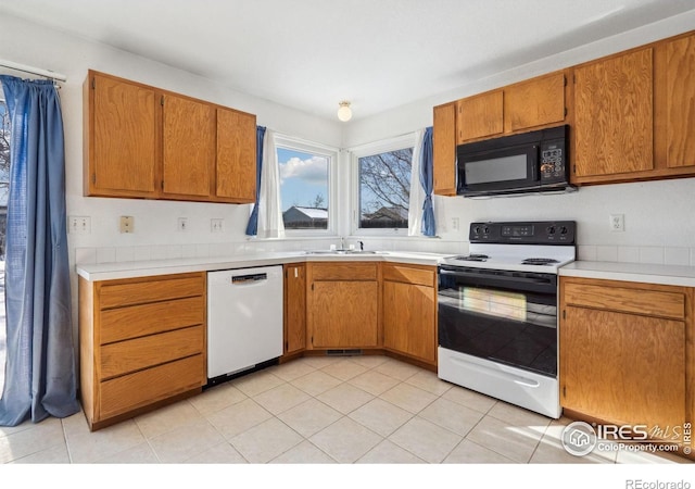 kitchen with electric stove, sink, white dishwasher, and light tile patterned floors