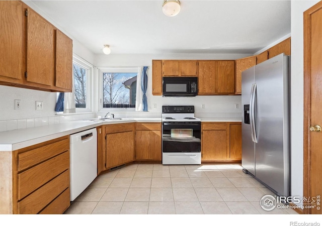 kitchen featuring electric stove, sink, stainless steel fridge, dishwasher, and light tile patterned flooring